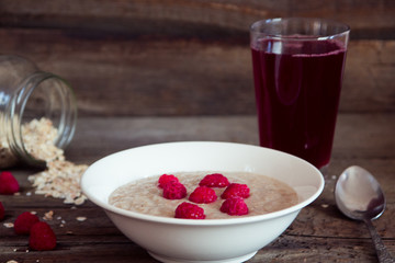 Oatmeal porridge with raspberries and compote on the wooden tabl