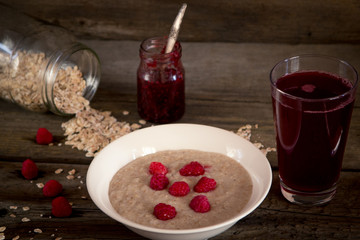 Oatmeal porridge with raspberries and compote on the wooden tabl