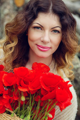 Naklejka premium beautiful young woman with a bouquet of poppies