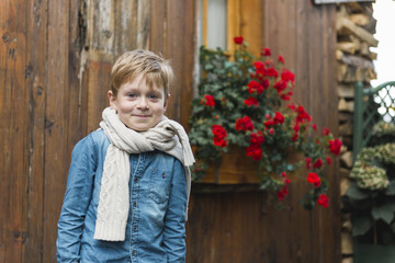 fashion boy smiling outdoors near red flowers