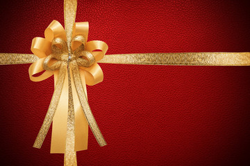 Golden ribbon with bow, on red leather paper texture, wrap gift box