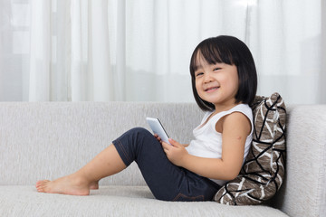 Asian Chinese little girl lying on the sofa with phone