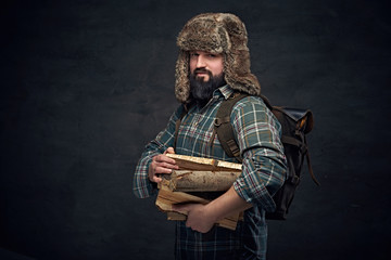 Middle age male holds backpack and firewoods.