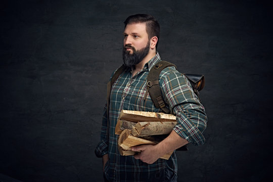 Middle age male holds backpack and firewoods.