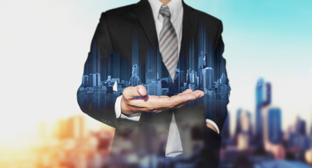 Businessman holding blue modern buildings hologram on hand, with black and white city background