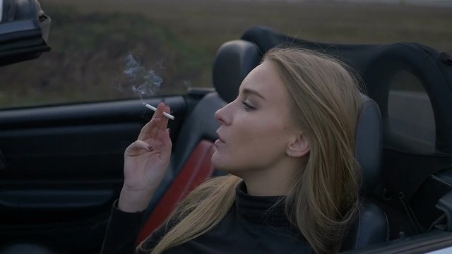 Young girl smoking in a convertible