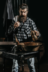 Bearded man shaves with razor