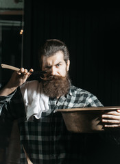 Bearded man shaves with razor