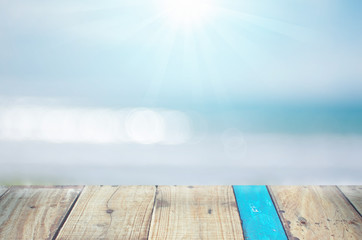 Obraz na płótnie Canvas Blur tropical beach with bokeh sun light wave on empty old wood table abstract background.