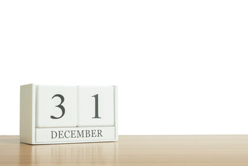 Closeup surface white wooden calendar with black 31 december word on blurred brown wood desk isolated on white background with copy space , selective focus at the calendar