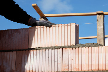 mason bricklayers hand is putting stone in close up