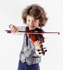 Cute curly-haired boy in a waistcoat playing the violin leaning forward. Close-up. Gray background.