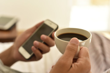 young man with a coffee using a smartphone