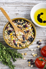 Assorted legumes grains on a light background with ripe tomatoes, olive oil, herbs, pepper ingredients for lunch or dinner. Top view. The concept of  healthy home-cooked meal.