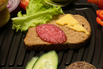 sandwich with cheese and sausage, vegetables around the grill