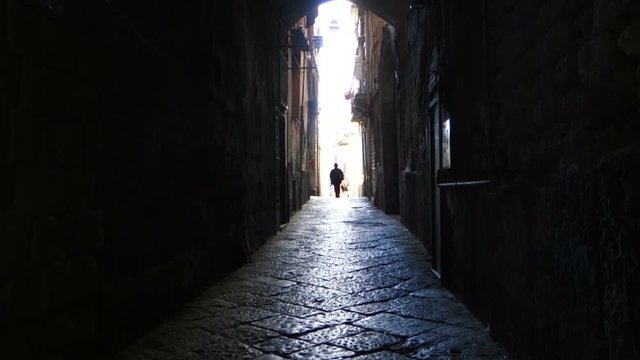 Silhouette of Elder woman walks in the alleys of the center of Naples, Italy