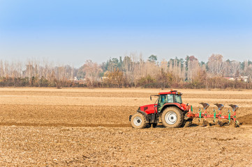Obraz premium Red Tractor Plowing in Autumn.