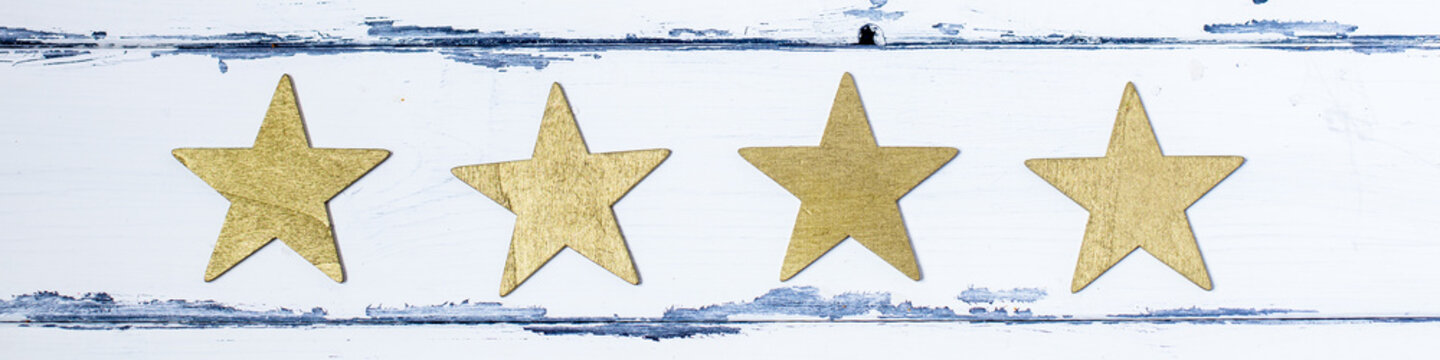 fyra gyllene stjärnor mot vit trä bakgrund horisontell panorama banner