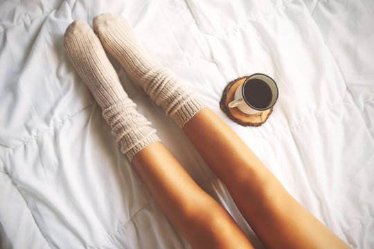 Soft photo of woman on the bed with cup of coffee, top view