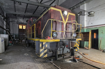 Old soviet shunting diesel locomotive in the abandoned room for servicing