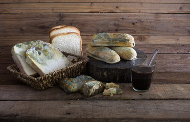 Rotten breads in basket and old chopping wood with black coffee