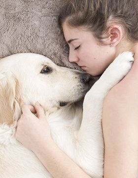 Teenage girl sleeping with her dog next to. Vertical shot with swab light from studio flax.