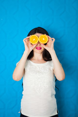 Beautiful close-up young pregnant woman with oranges on blue bac