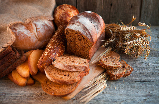 Assortment of fresh baked bread on wooden table background