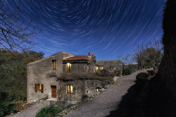 Old mill in Corsica at night with star trails above