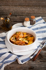 Oven-baked chicken legs with potatoes, on rustik wooden backgrou