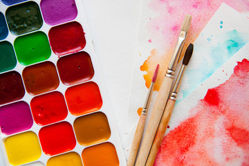 Fototapeta premium Top view Palette of watercolor paints, brushes and paper for a w