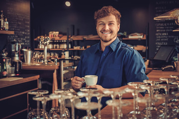 Handsome barista tasting a new type of coffee in his coffee shop