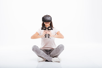 Obraz na płótnie Canvas Happy young lady wearing virtual reality device holding joysticks