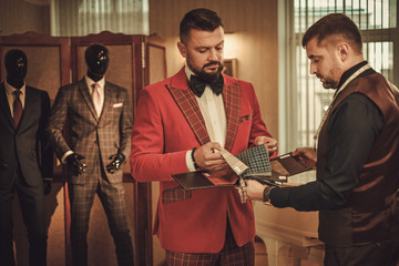 Extravagant man in tailor studio choosing cloth for custom made suit