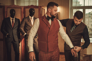 Tailor measuring client for custom made suit tailoring