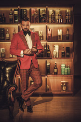 Extravagant stylish man with whisky glass and cigar in gentleman club