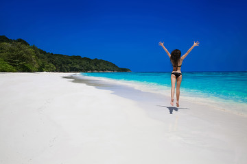 Fototapeta na wymiar Summer vacation. Beautiful free woman jumping on the exotic sea