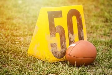 American football ball next to 50 yard marker.