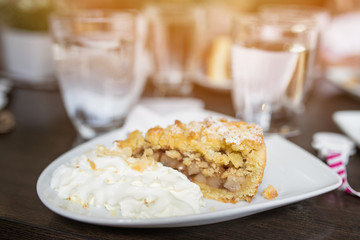 Slice of home made apple pie with whipped cream on a plate.