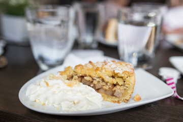 Slice of home made apple pie with whipped cream on a plate.