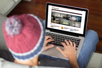 Young man on the sofa reading online magazine