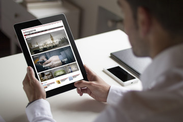 businessman reading online magazine with tablet pc © MclittleStock