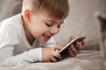 Cheerful boy holding smartphone and playing game