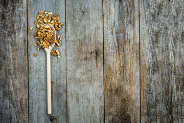 Spoon with walnuts on wooden background, seeds for healthy eating, top view
