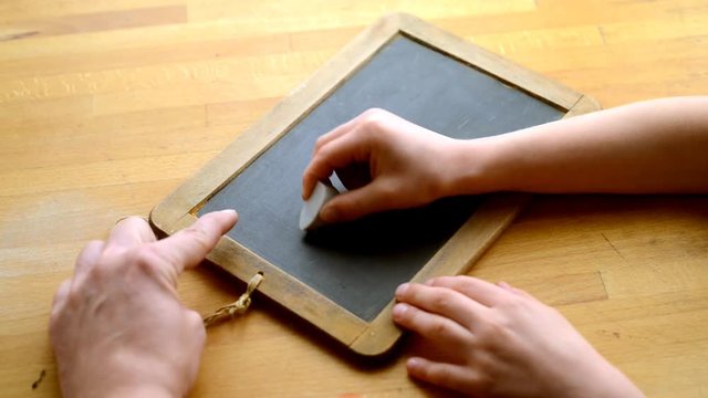 Kind schreibt eine Rechenaufgabe auf eine Kreidetafel