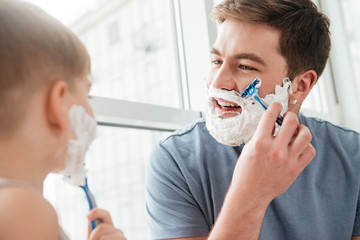 Young father and son shaving in bathroom