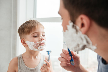 Funny father and son shaving in bathroom