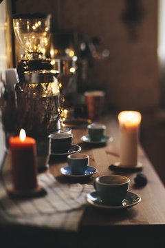 Beautiful festive evening table served. On the wooden table: colorful coffee cups with saucers,napkin, burning candles and some christmas fireflies