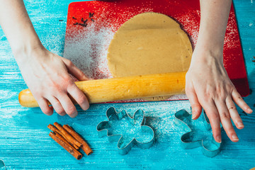 girl rolls the dough on the red board to blue wooden table