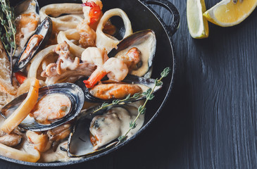 Seafood Stew in Saucepan closeup on dark wood background